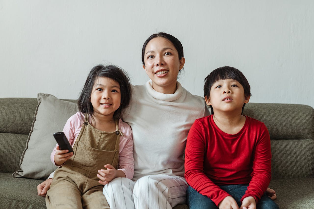 gallery-03 Mother and children enjoying television time together at home on a comfortable sofa.